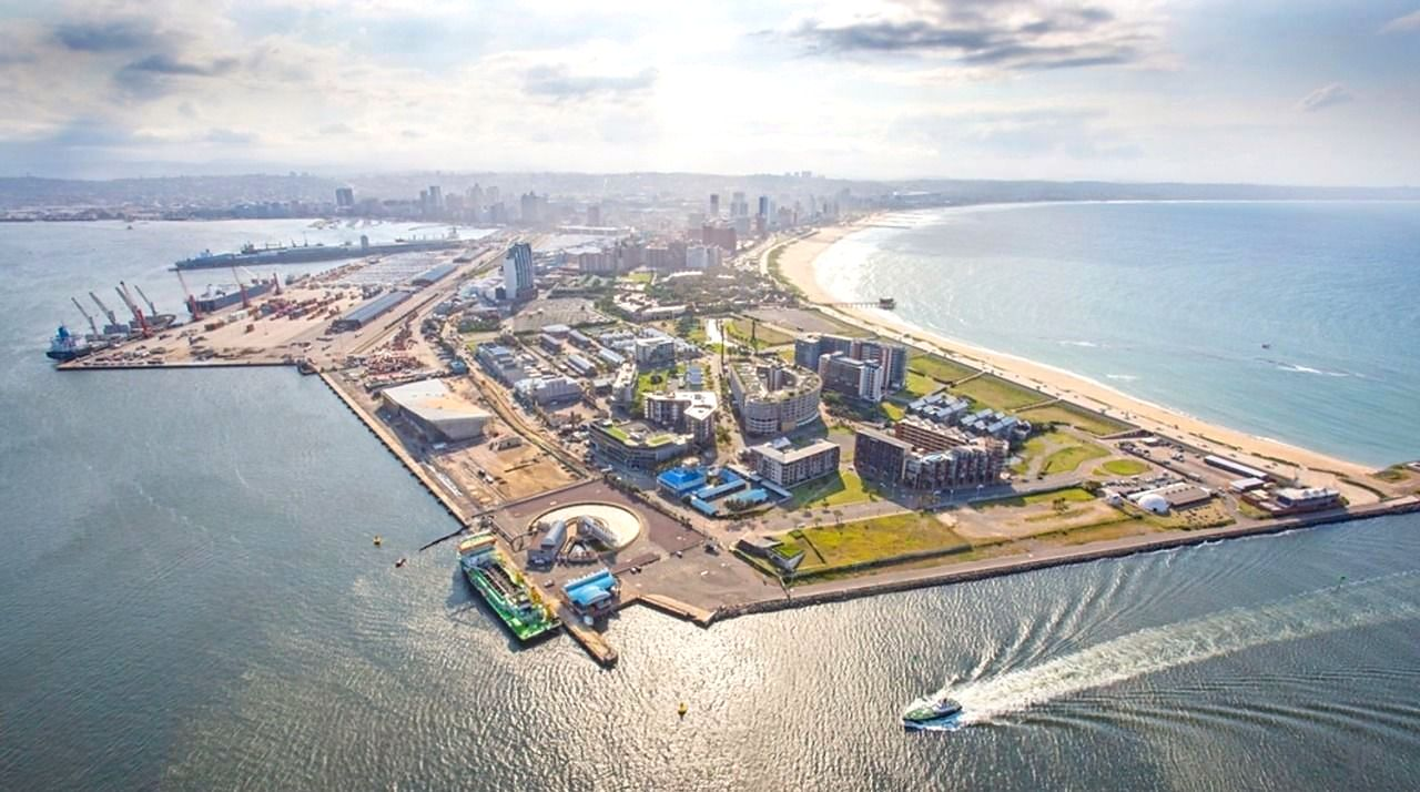 Aerial view of Durban's Point Waterfront at the harbour mouth — ocean beach on one side, working harbour on the other